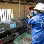 Trabalhador usando equipamento de processamento de minério em uma instalação industrial.