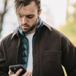 Homem recebe uma mensagem no celular enquanto está em uma rua.