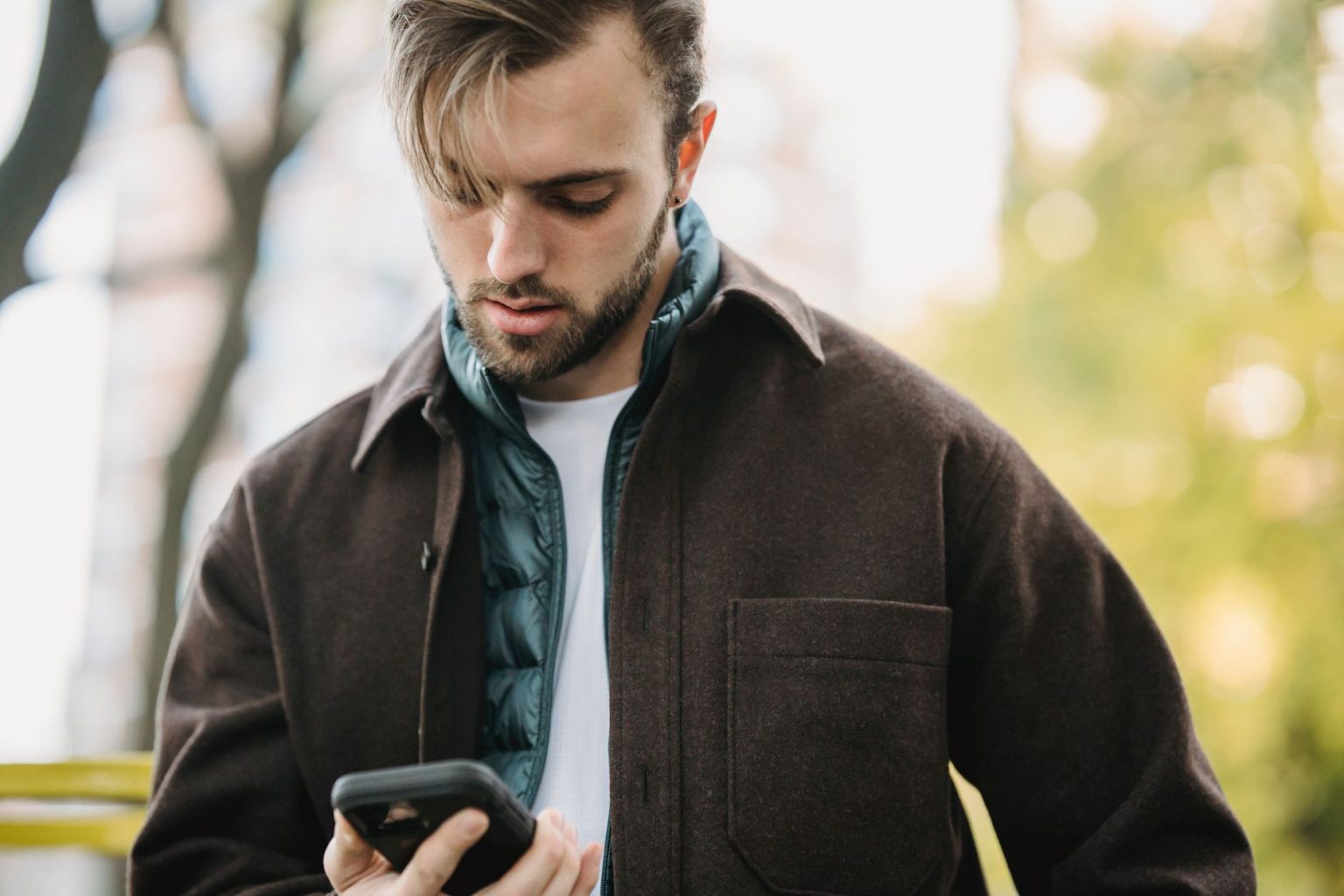 Homem recebe uma mensagem no celular enquanto está em uma rua.