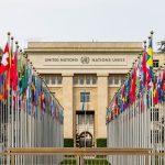 Edifício do escritório da ONU em Genebra cercado por bandeiras de diversos países.