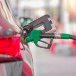 Bocal de abastecimento inserido no tanque de um carro em um posto de combustíveis.