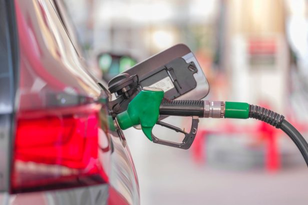 Bocal de abastecimento inserido no tanque de um carro em um posto de combustíveis.