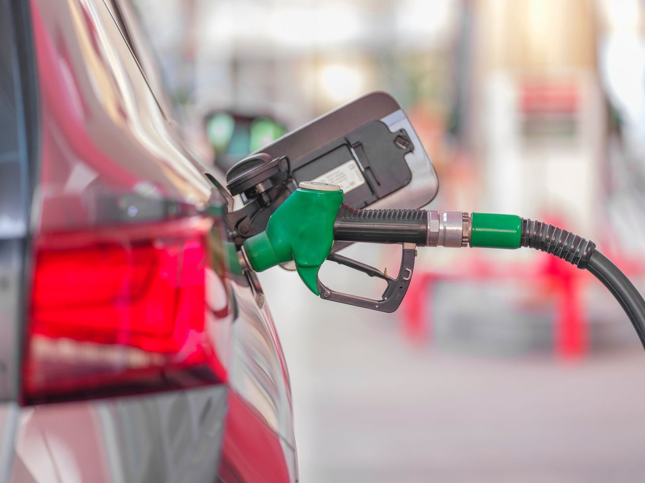 Bocal de abastecimento inserido no tanque de um carro em um posto de combustíveis.