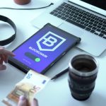 Tablet exibindo uma transação digital ao lado de um laptop e cédulas de euro.